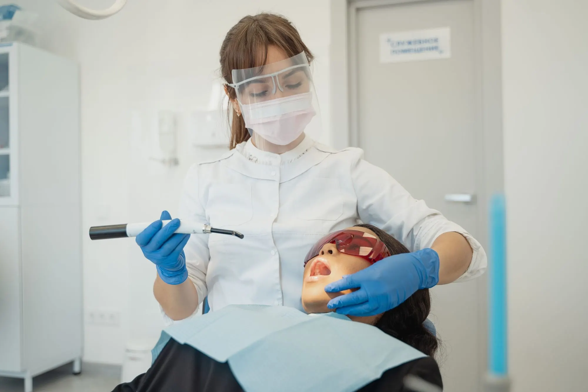 Dentist setting a tooth-coloured filling with a curing light